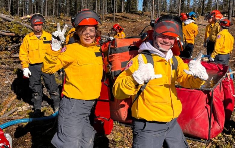 Two firefighters holding equipment and smiling. 