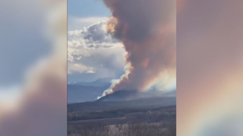 A wildfire burns next to a hill amid dry conditions.