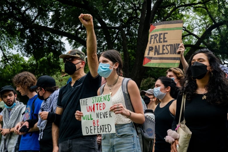 A line of protesters with some holding cardboard signs. 