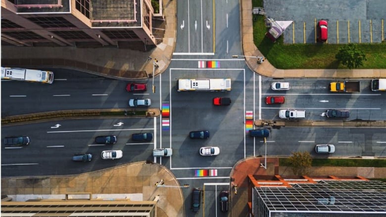 A drone view shows cars waiting at the intersection with city buildings