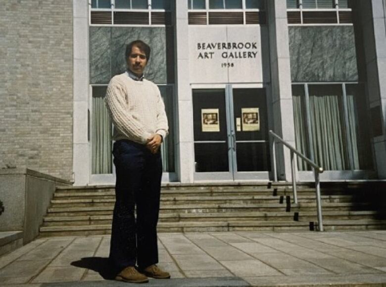 A photo of a man standing outside of a building that says 