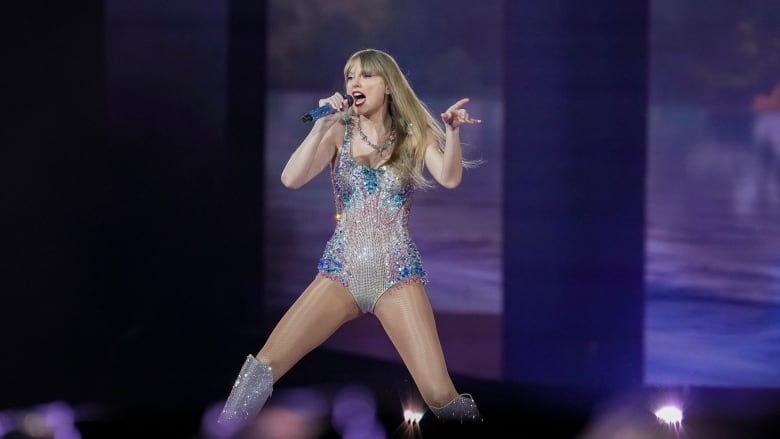 A woman in a sparkly bodysuit sings into a microphone on a stage