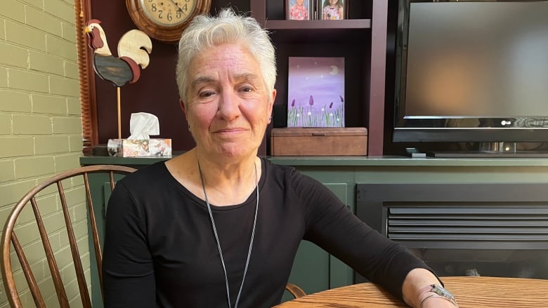 A woman in a black shirt sits at a table.