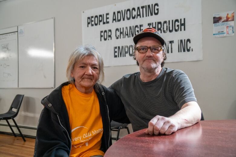 Two people sit at a table inside.