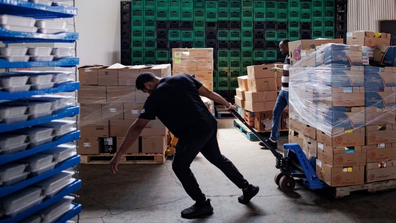 A man pulls on a trolley carrying piles of boxes filled with food donations.