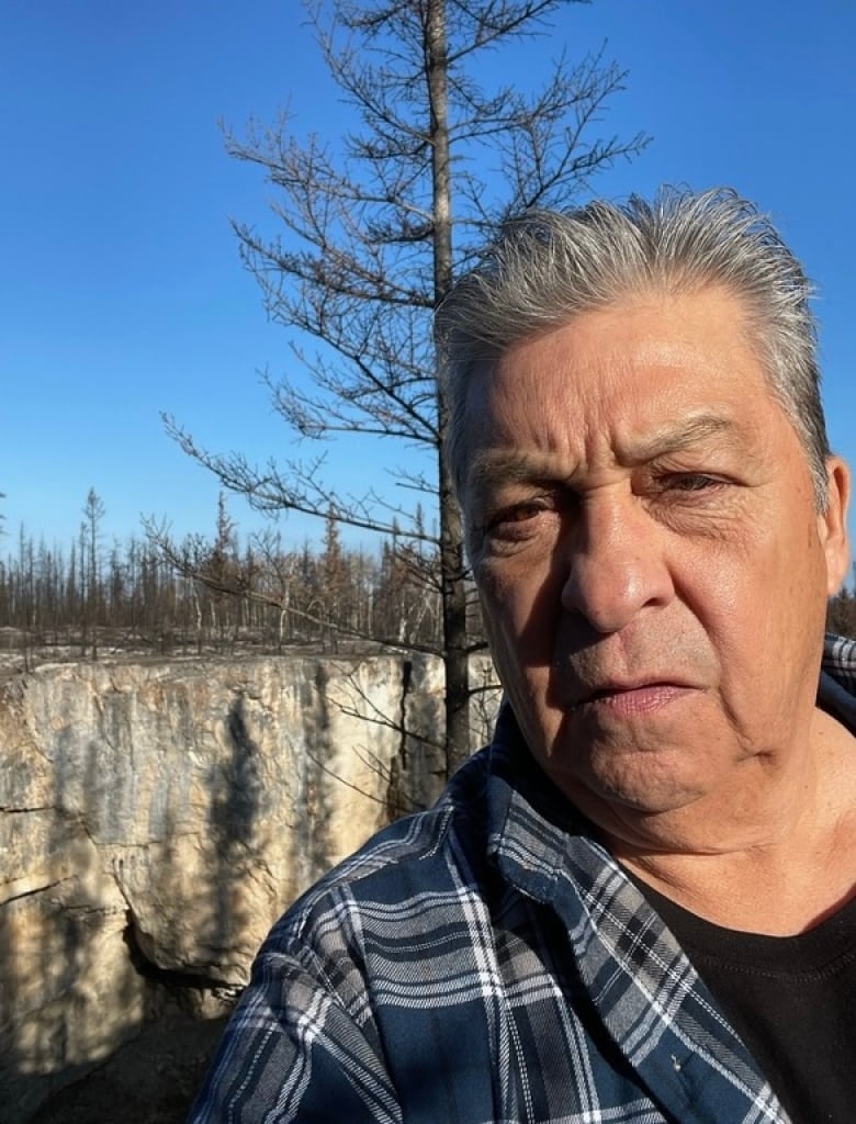 A selfie image of a man with trees in the background 