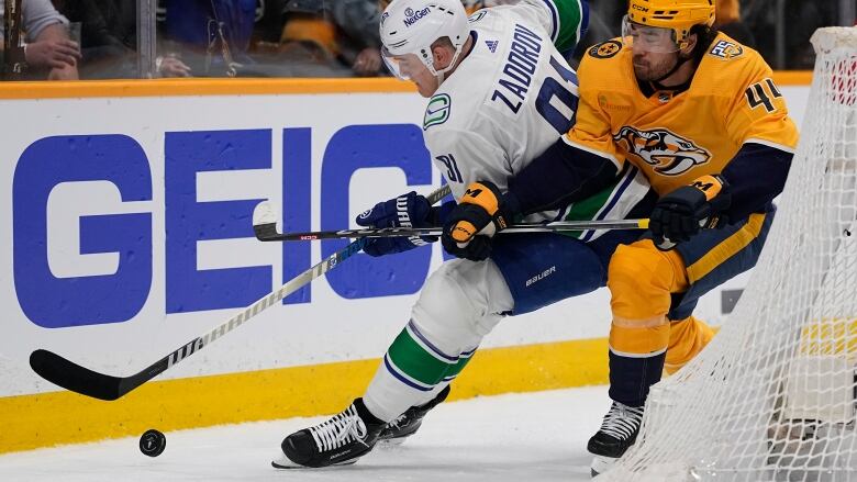 Two hockey players fight for the puck.