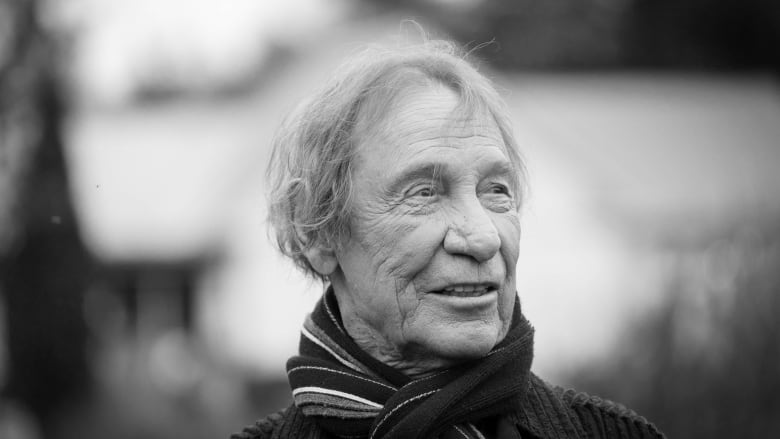 Black and white portrait of an older man wearing a scarf.