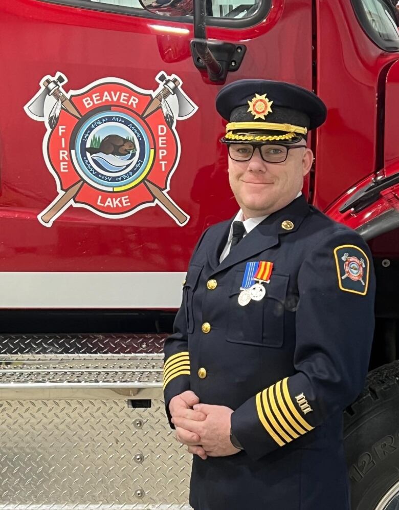 Man in fire chief uniform, standing next to a firetruck with logo that reads Beaver Lake Fire Department. 