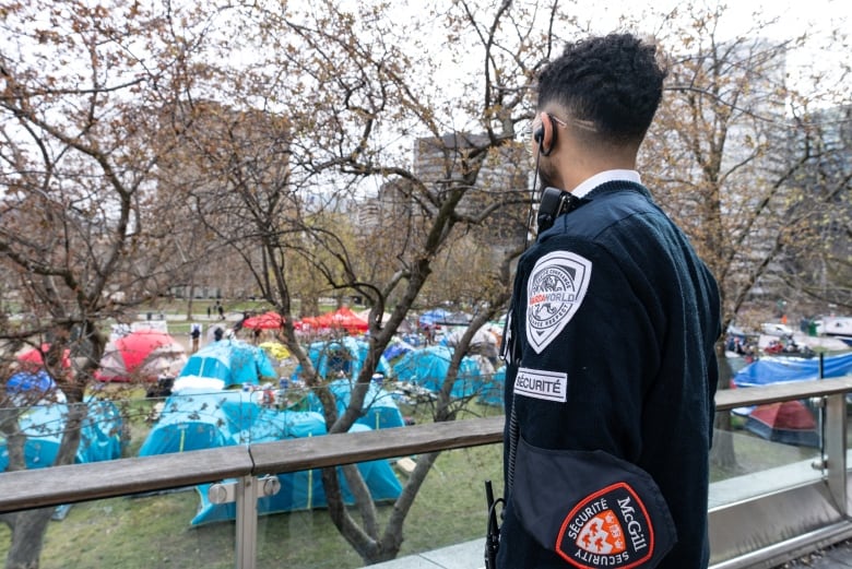 security guard dressed in blue looks over tents on grass