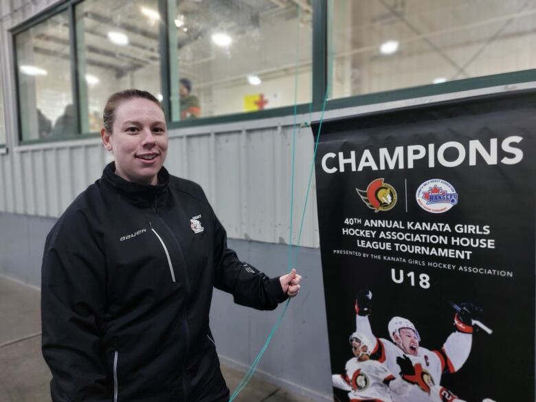 Iqaluit Blizzards coach Lauren Perrin holds the rope to hang the team's victory banner.