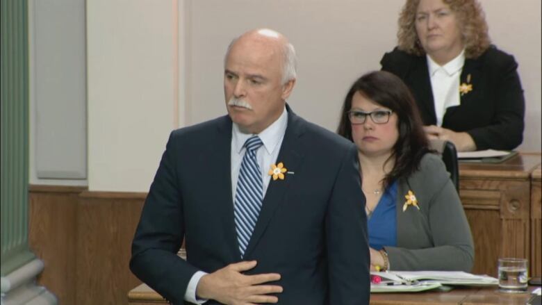 Man with white mustache in grey suit.