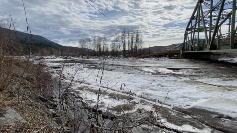 A bunch of ice in a river under a bridge.