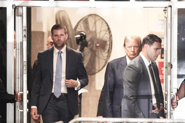 Men in suits and ties are shown walking indoors.