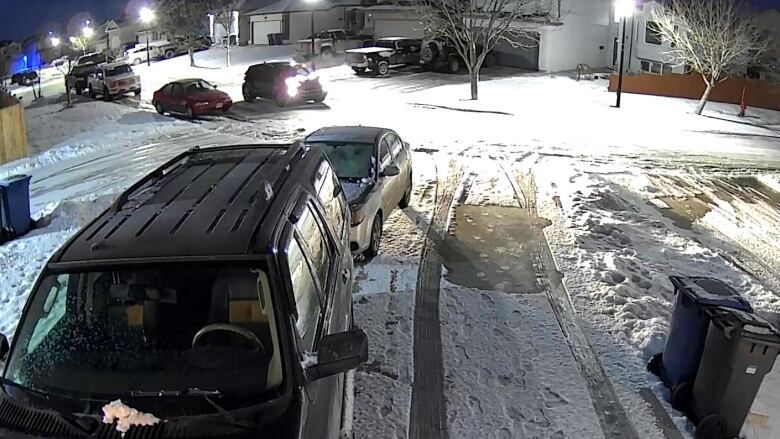 A suburban street with a vehicle on the road. Muzzle flash and smoke can be seen emanating from the driver's side of the vehicle.