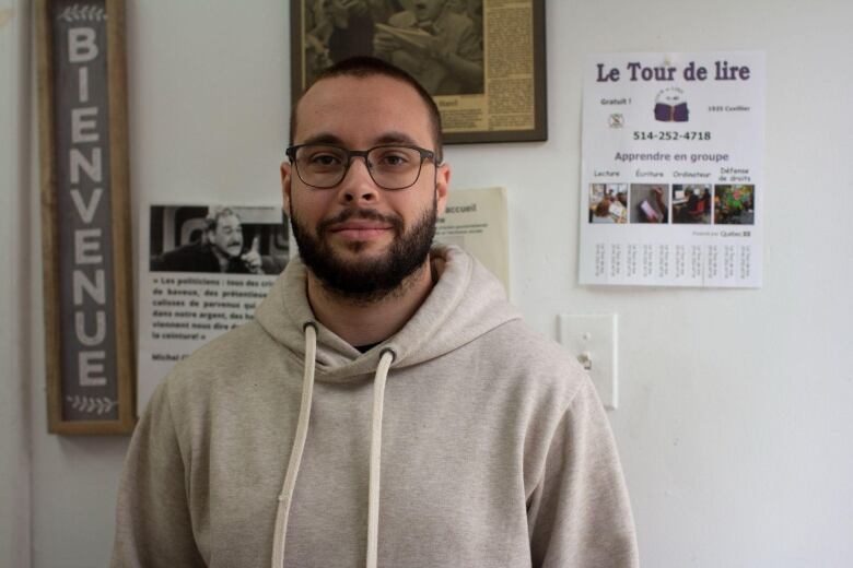 A man wearing a beige hoodie smiles. 