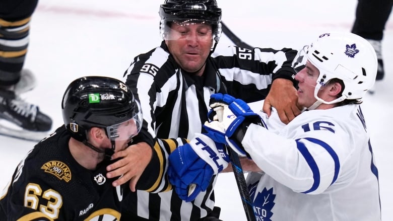 NHL linesman Jonny Murray, center, tries to separate Boston Bruins left wing Brad Marchand (63) and Toronto Maple Leafs right wing Mitch Marner (16) during the second period of Game 5 of an NHL hockey Stanley Cup first-round playoff series, Tuesday, April 30, 2024, in Boston. (AP Photo/Charles Krupa)