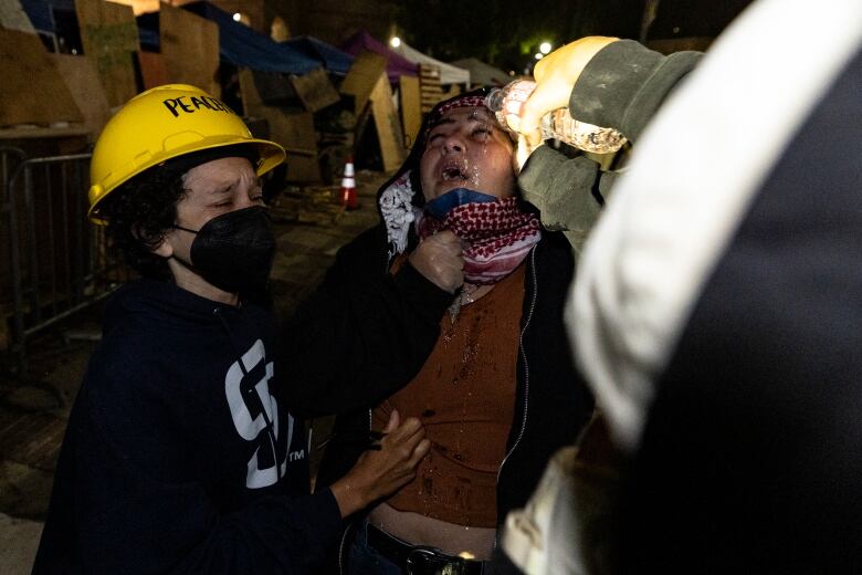 A woman lowers a handkerchief to receive water on her face from a bottle in a nighttime photo.