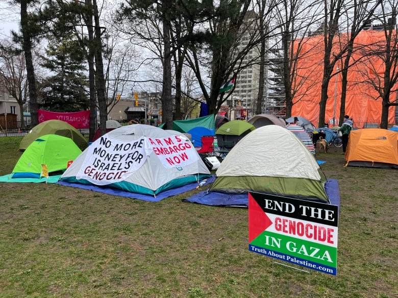 Tents and a lawn sign with trees in the background.