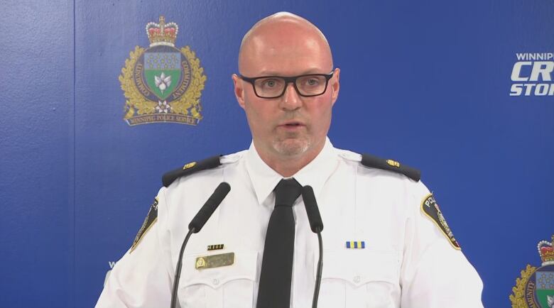 A bald man with eyeglasses and a goatee is dressed in a white, collared shirt.