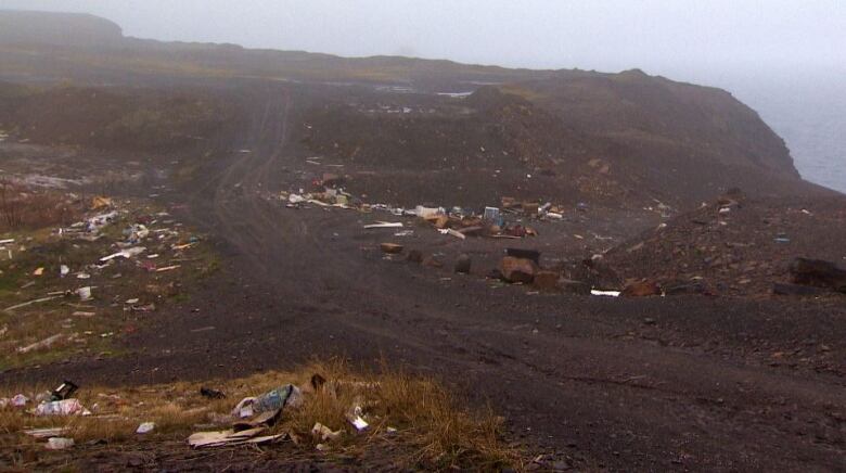 A dirt road with litter and garbage. 