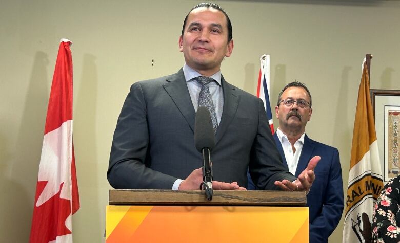 A man stands behind a podium in front of another man.