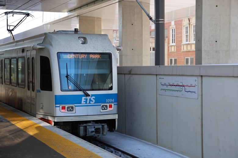 a city transit train that is blue and white pulls up to a cement train station platform.