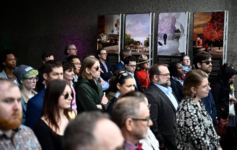 A crowd of people standing and looking at someone speaking, not in the frame.