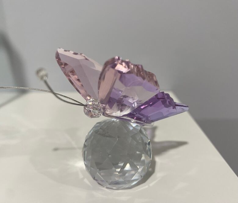 A little glass butterfly with pink and purple wings.