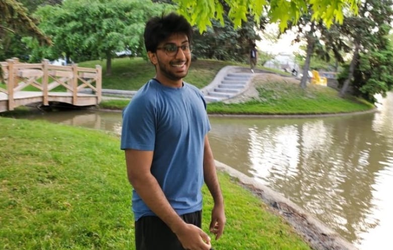 A young Pakistani-Canadian man walks in a picturesque garden.