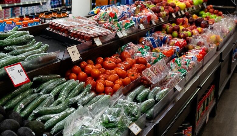 Cucumbers, tomatoes and other vegetables on display in a grocery store.