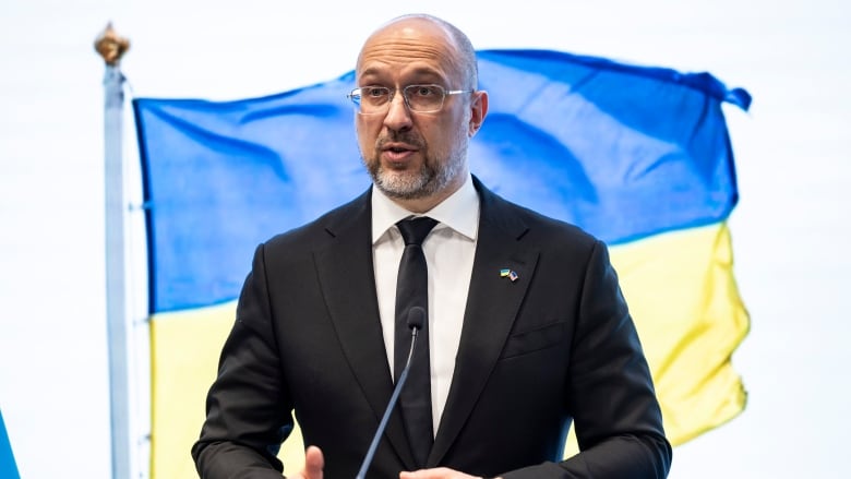 Ukraine Prime Minister Denys Shmyhal speaks at podium in front of Ukraine flag