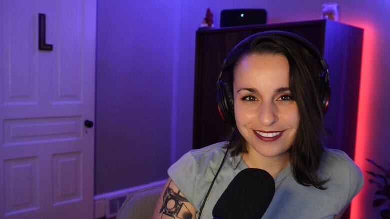 woman sits in front of a microphone in a dark room 