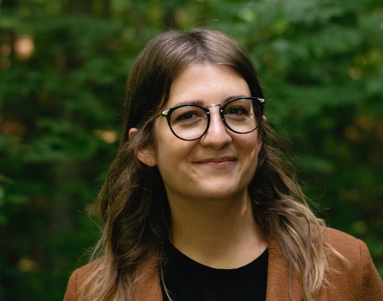 woman stands against a tree in glasses