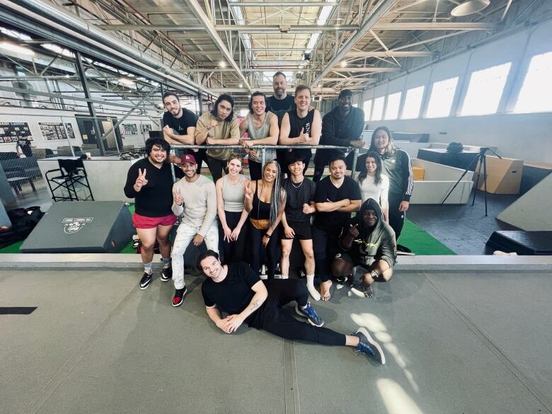 A smiling group of athletic looking people pose in a gym. 