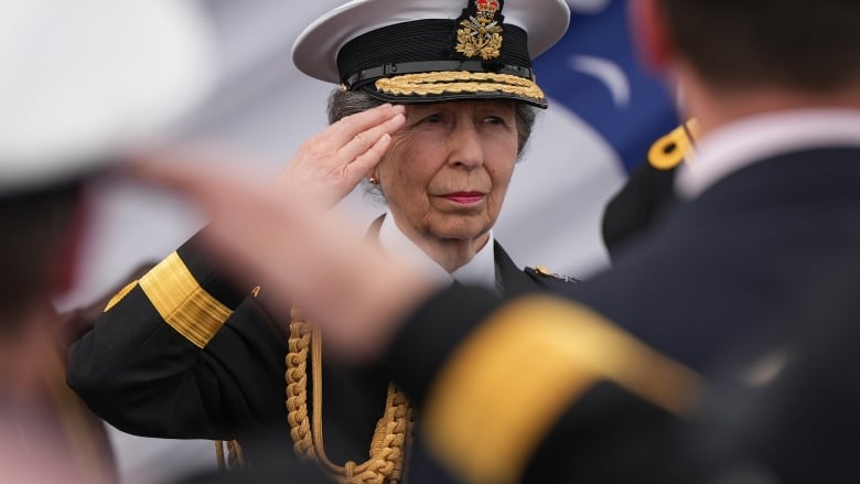 A woman in a naval uniform salutes.