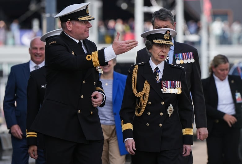 Two people walk wearing uniforms.