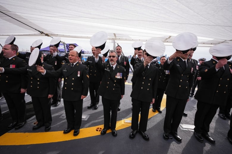 Sailors raise their caps.