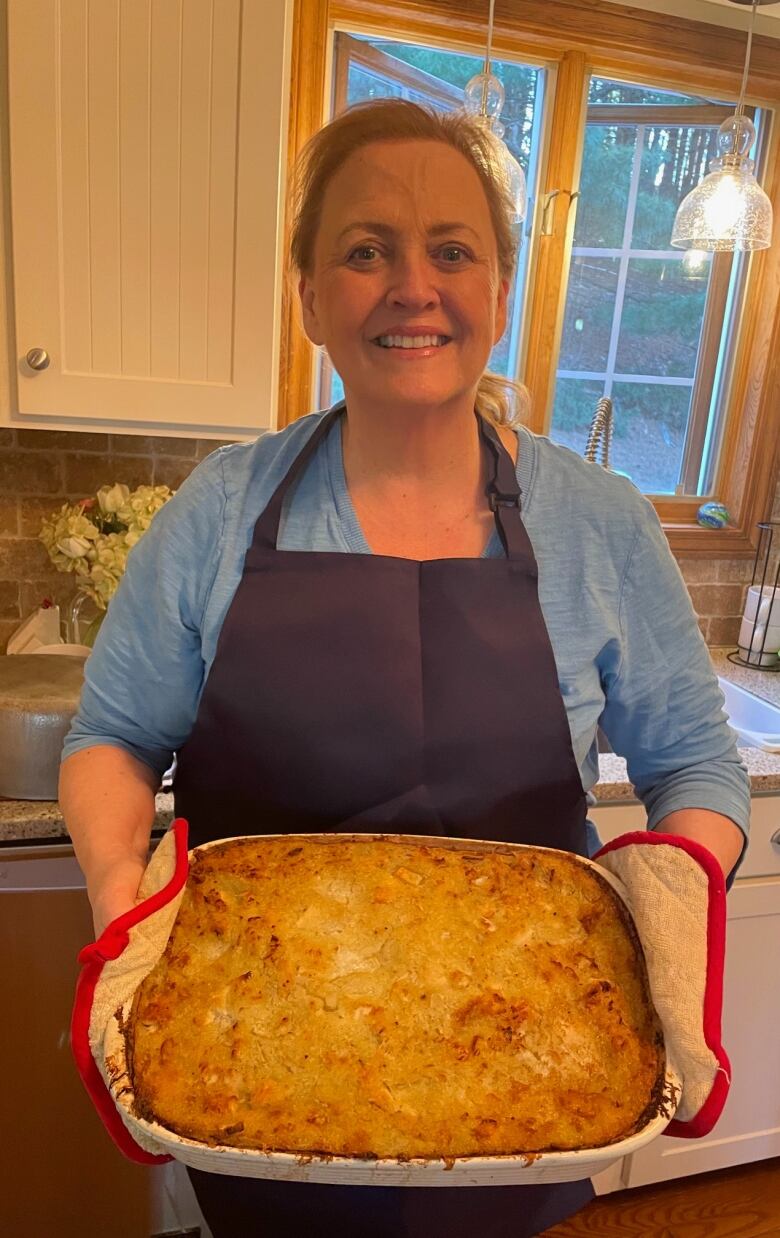 A woman shows off a rappie pie she made.