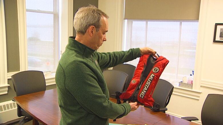 Man looks at life jacket.