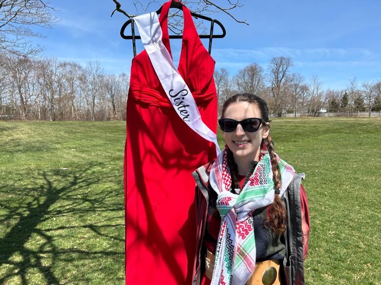 Mi'kmaq woman standing beside red dress.