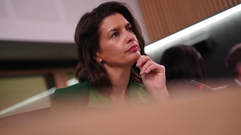 Woman wearing green blazer sits in front of microphone