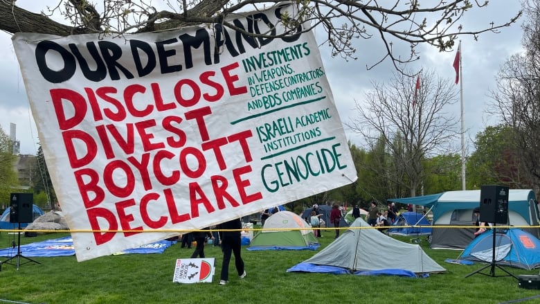 A sign with tents in the background.