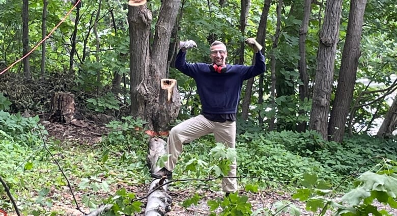 A photo of a man flexing his muscles in the forest.