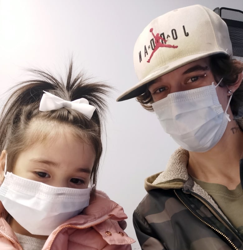 A little girl and a man wearing surgical masks.