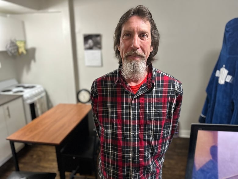 A man in a red plaid shirt in a home.