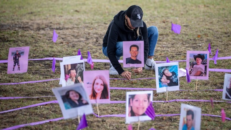 A person places a stake in the ground with a photo of someone who died from toxic drugs