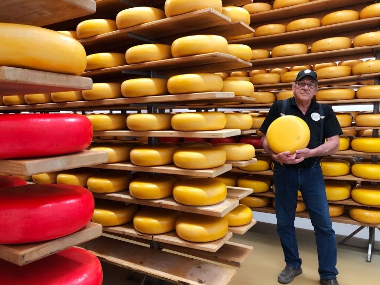 man stands with cheese wheels