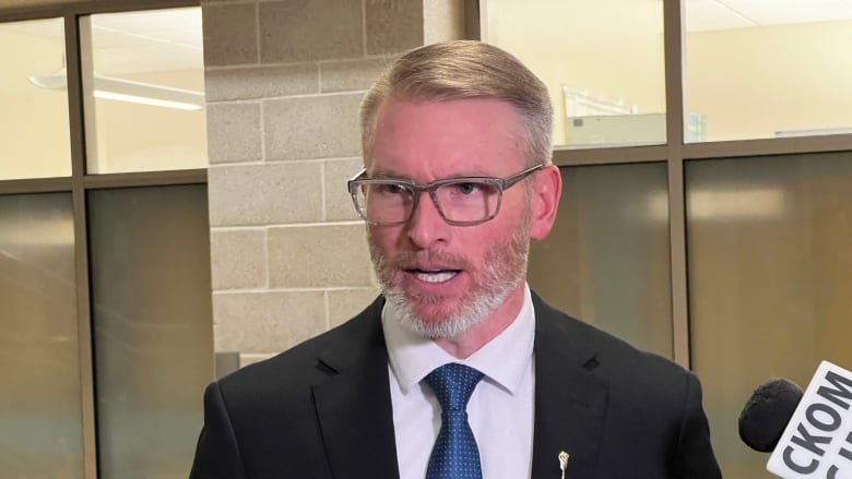 A man in a black suit and glasses