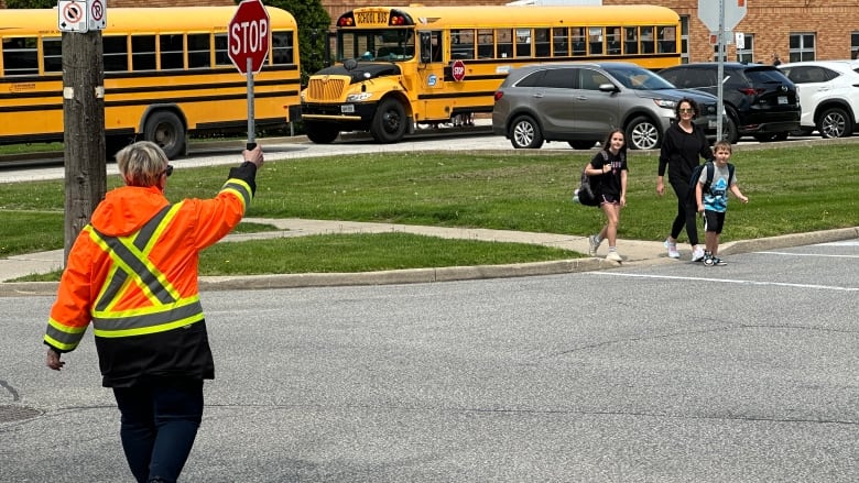 A crossing guard at St. Pius X school in Tecumseh helps people across the road.